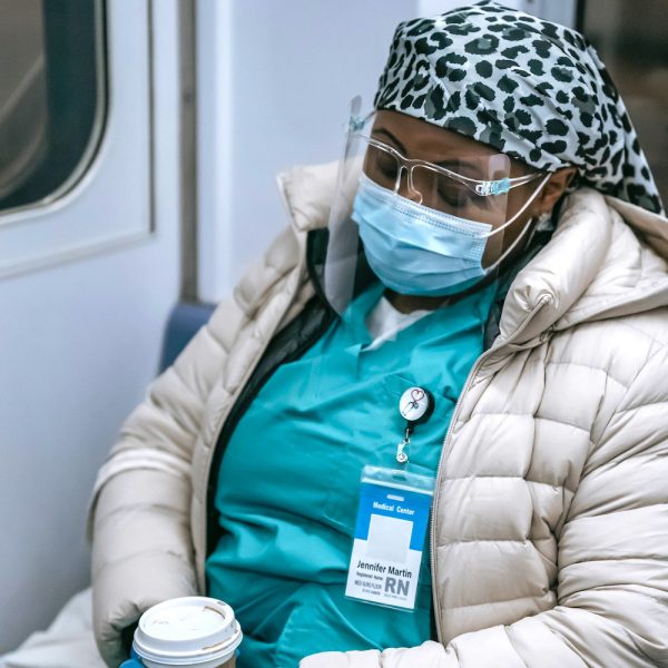 Black woman doctor sleeping on train with coat and mask on